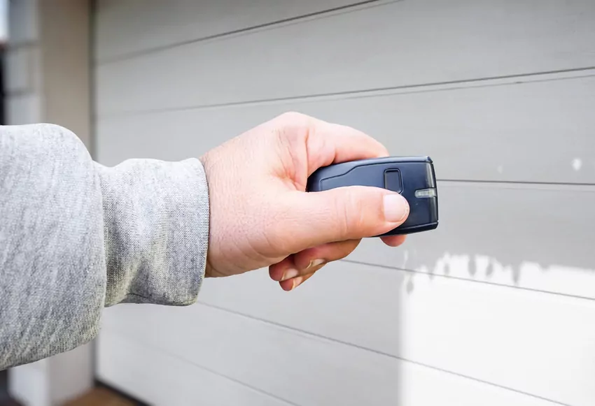 Męska dłoń trzymająca pilot do bramy automatycznej