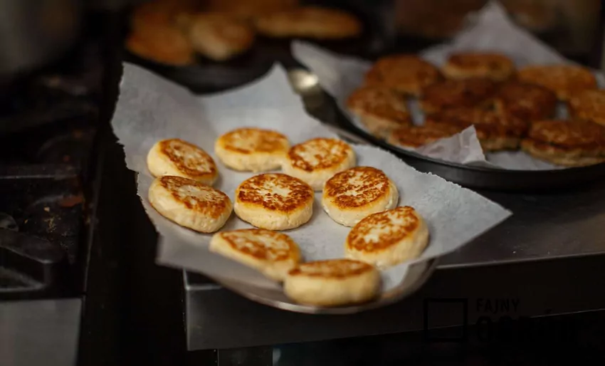 Syrniki ułożone na talerzu wyłożonym ręcznikiem papierowym