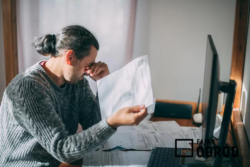 Załamany mężczyzna z rachunkami przy biurku