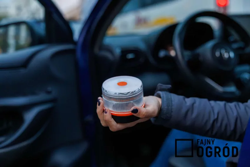 Kierowca samochodu wyciąga dłoń z lampą V-16