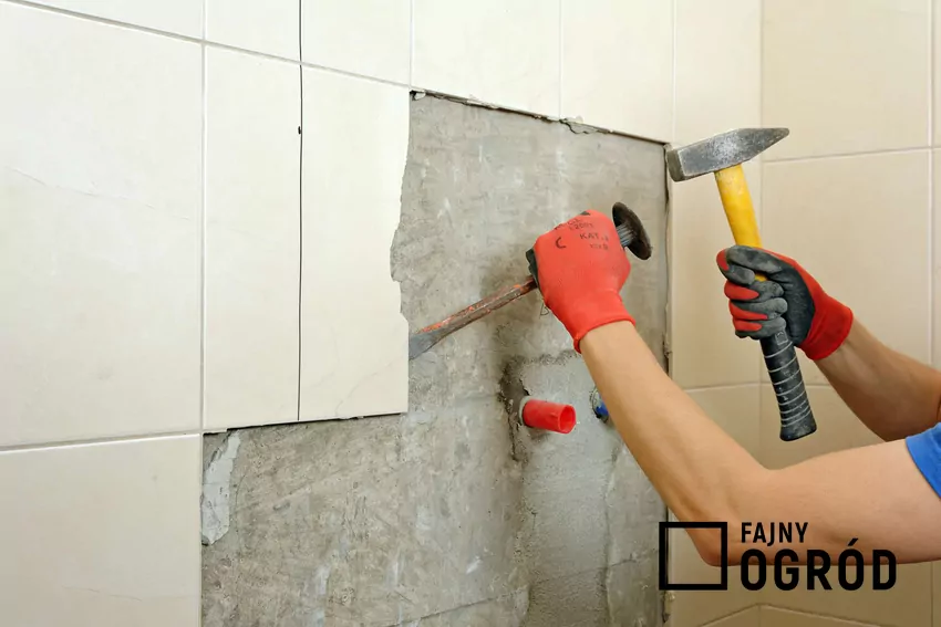 Fachowiec skuwa płytki na ścianie łazienki