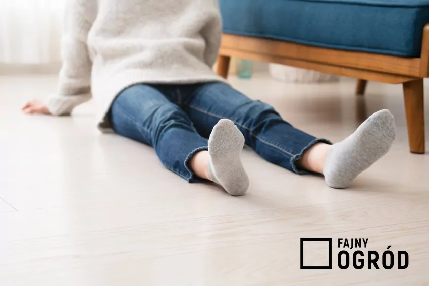 Nieodpowiednio użytkowana podłogówka jest narażona na poważne awarie człowiek siedzi na ciepłej podłodze